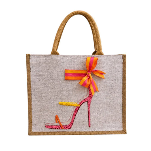 Hand-painted jute tote bag featuring a colorful pink, orange, and yellow embellished stiletto sandal with a striped bow detail and natural woven handles.