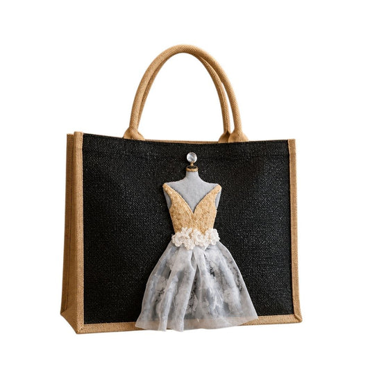 Hand-painted black jute tote bag featuring a dimensional embellished dress design in gold, ivory, and sheer floral fabric against a black background. Elegant bridal-inspired statement tote with textured mixed-media details, natural jute trim, double handles, and magnetic snap closure. Perfect for weddings, bridal showers, fashion lovers, and unique handmade gift giving.