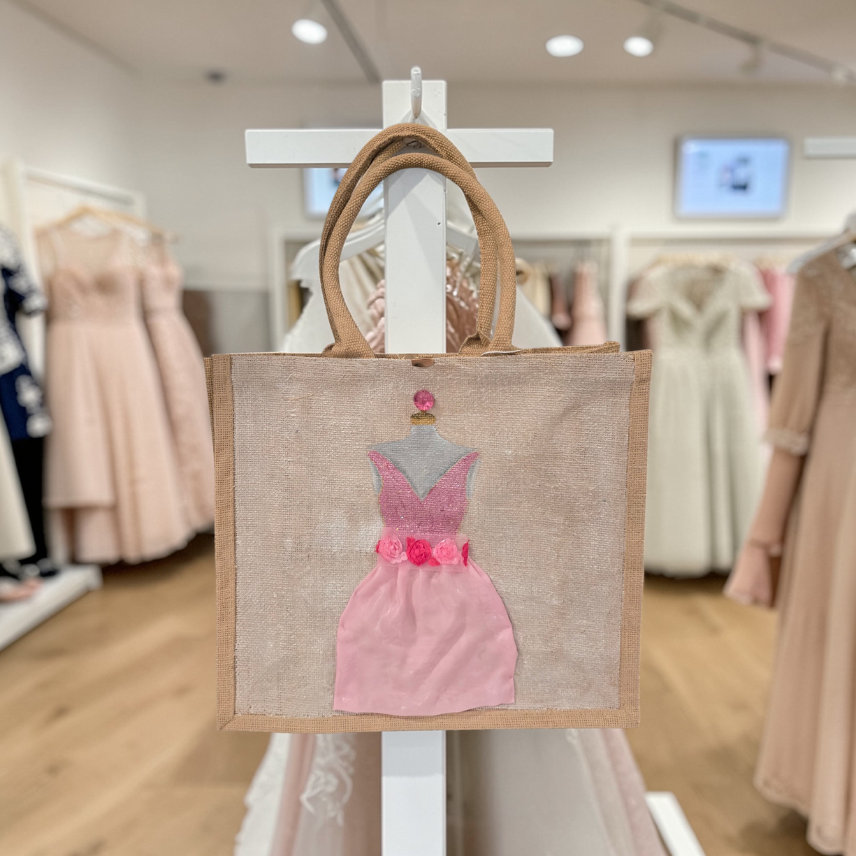 Hand-painted jute tote bag featuring a blush pink bridesmaid dress with floral details on a natural canvas background