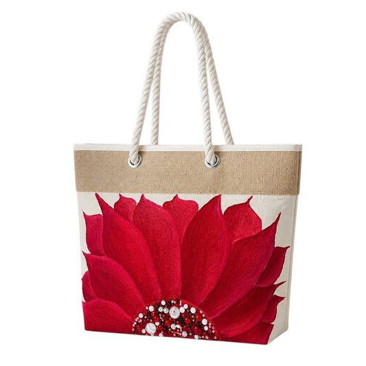 Hand-painted rope handle beach tote featuring a bold red floral design with jeweled embellishments at the flower center, accented with natural jute trim and oversized white rope handles against a neutral background.