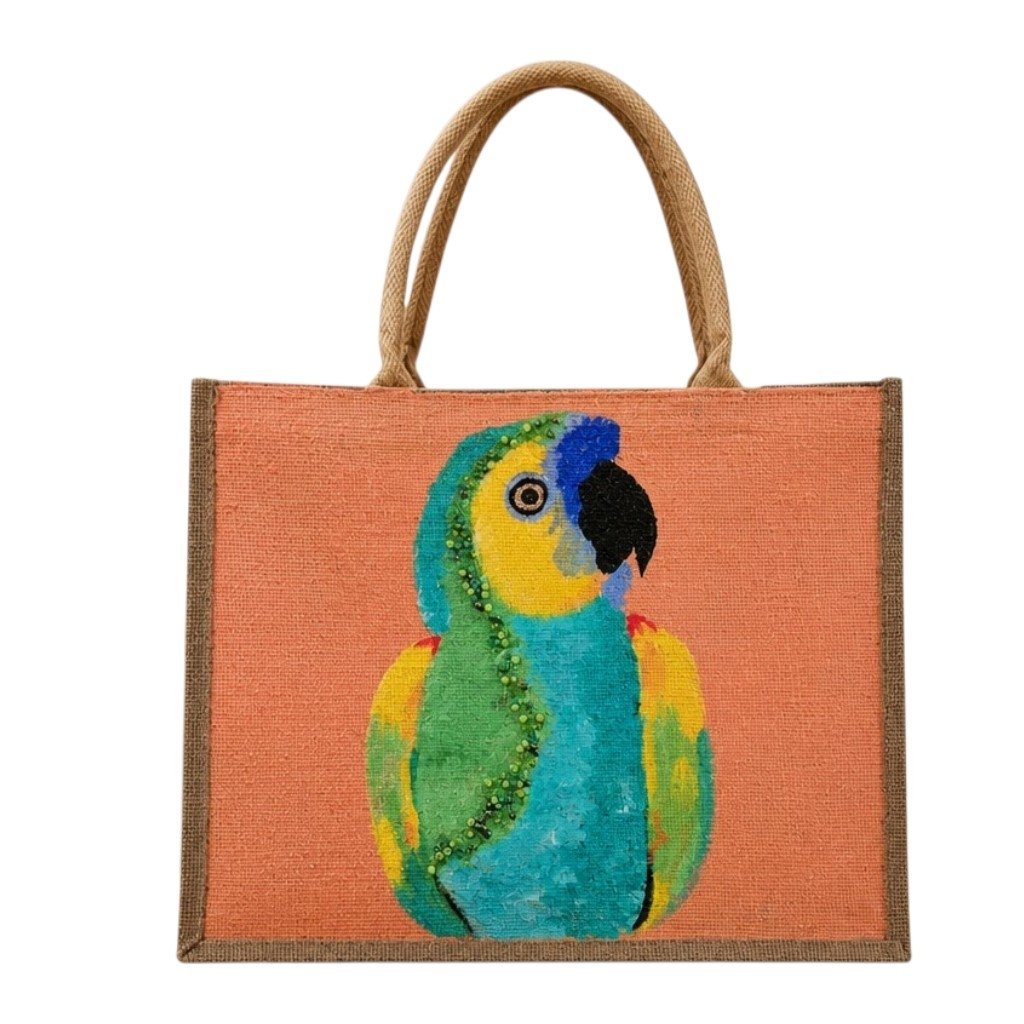 Hand-painted tropical parrot tote bag on natural jute canvas featuring a colorful blue, green, and yellow parrot against a coral-orange background, finished with sturdy double handles and a structured rectangular shape.
