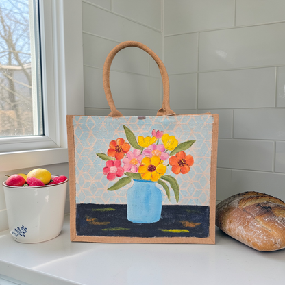 Hand-painted jute tote bag featuring colorful flowers in a blue vase against a light patterned background