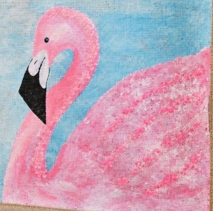 close up of Hand-painted flamingo tote bag on natural jute canvas featuring a large pink flamingo against a soft blue background, finished with sturdy double handles and a structured rectangular silhouette.
