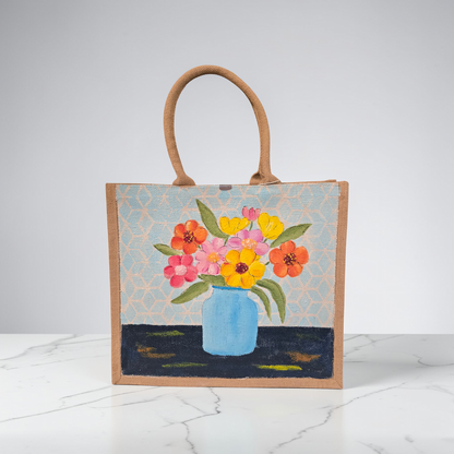 Hand-painted jute tote bag featuring colorful flowers in a blue vase against a light patterned background