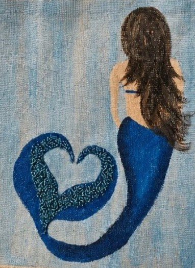 Close up of Hand-painted jute tote bag featuring a blue mermaid with flowing brown hair and a heart-shaped tail design on a soft blue background, accented with glitter details and natural burlap handles.