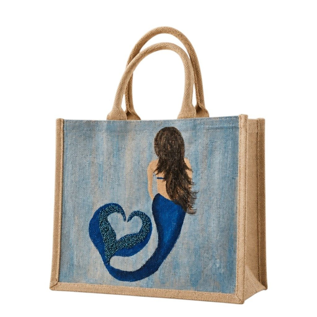 Hand-painted jute tote bag featuring a blue mermaid with flowing brown hair and a heart-shaped tail design on a soft blue background, accented with glitter details and natural burlap handles.
