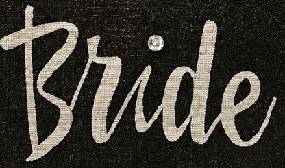close up of Hand-painted black jute tote bag featuring the word “Bride” in bold white script with a rhinestone accent, designed for weddings, bridal celebrations, and stylish bride-to-be gifts.