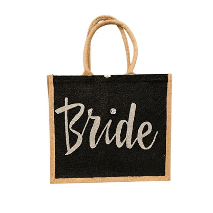 Hand-painted black jute tote bag featuring the word “Bride” in bold white script with a rhinestone accent, designed for weddings, bridal celebrations, and stylish bride-to-be gifts.