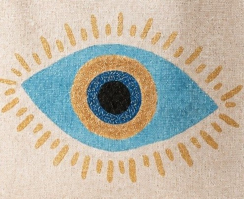 close up of Hand-painted jute tote bag featuring a blue and gold evil eye design centered on a natural canvas background, accented with metallic gold detailing, natural jute trim, and rounded padded handles.