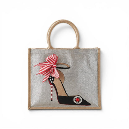 Hand-painted jute tote bag featuring a black stiletto shoe with a red-and-white striped heel, star accents, a striped bow, and a sparkling red jewel embellishment on a silver background.