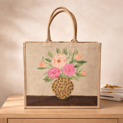 Hand-painted jute tote bag featuring pink and peach flowers arranged in a leopard print vase on a natural canvas background