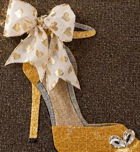 close up of Hand-painted jute tote bag featuring a gold glitter stiletto shoe on a dark background, accented with a sheer ivory bow with metallic heart details and crystal embellishments.