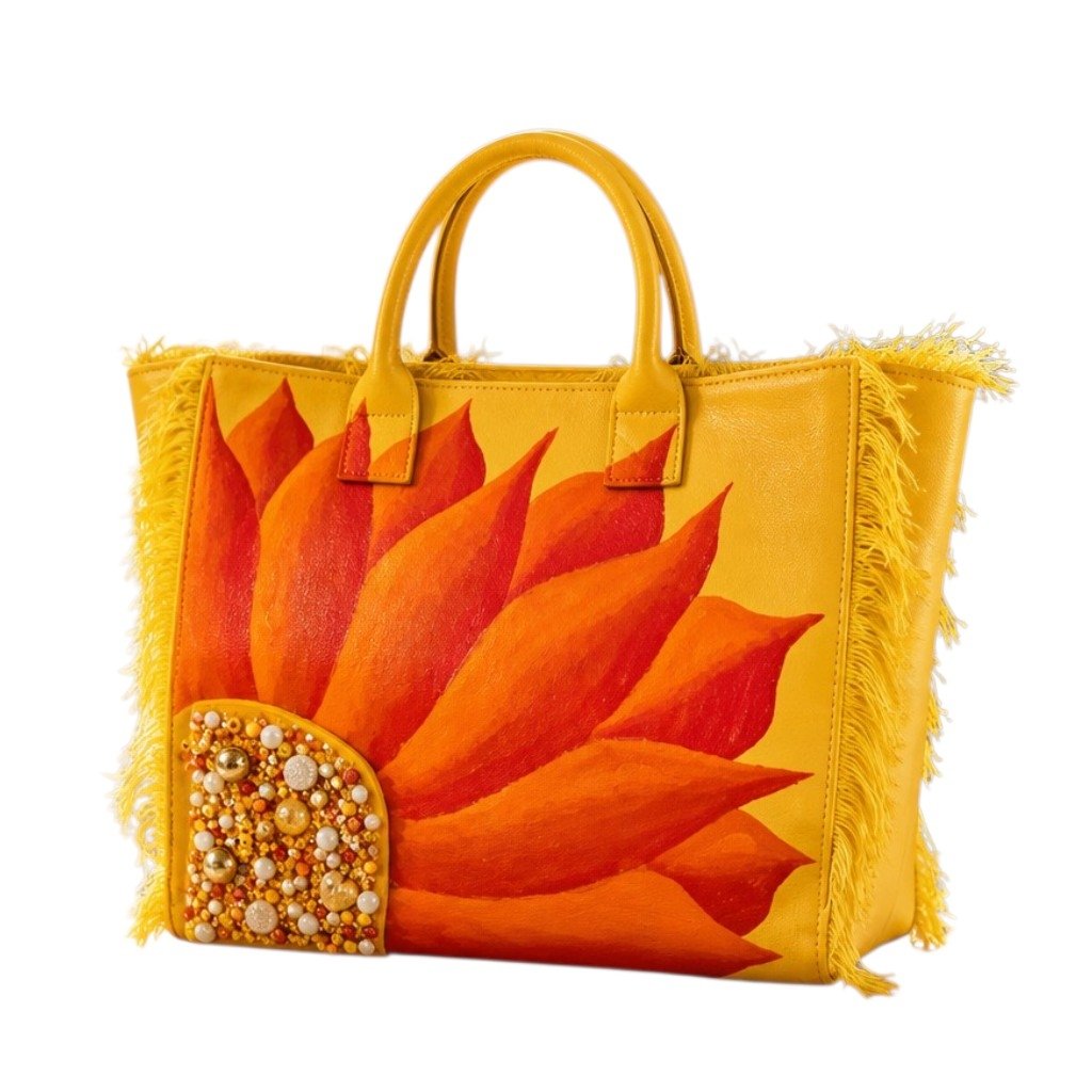 Hand-painted yellow fringed tote bag featuring a bold sunflower design in vibrant orange and red tones, accented with pearl and gold embellishments on the flower center, displayed against a neutral background.