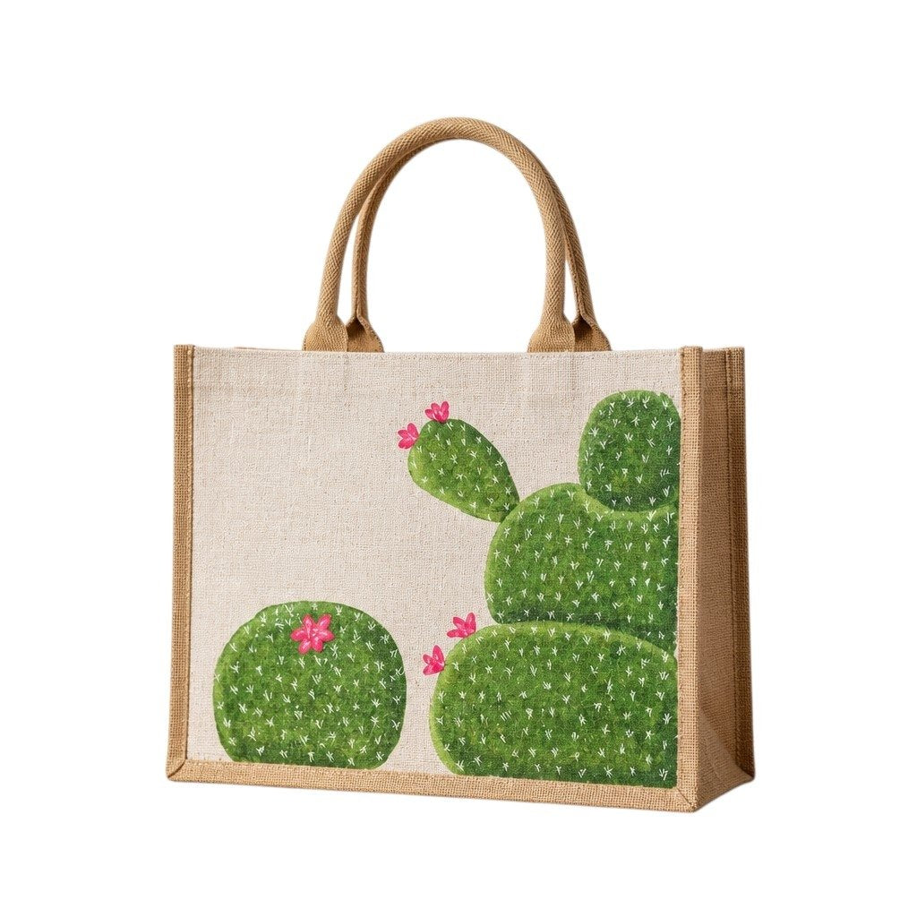 Hand-painted cactus tote bag featuring whimsical green cactus designs with pink blooms on a natural canvas background, accented with jute trim and rounded padded handles against a neutral background.