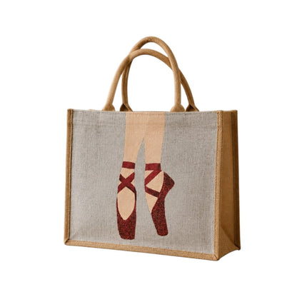 Hand-painted jute tote bag featuring elegant red ballet pointe shoes on a soft neutral background. This dance-inspired tote combines natural woven textures with graceful ballet imagery, creating a stylish and artistic accessory for dancers and ballet lovers.