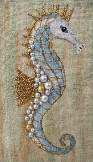 Close up of Hand-painted jute tote bag featuring a soft blue seahorse embellished with pearls and gold accents on a textured seafoam green background, finished with natural burlap handles and trim.