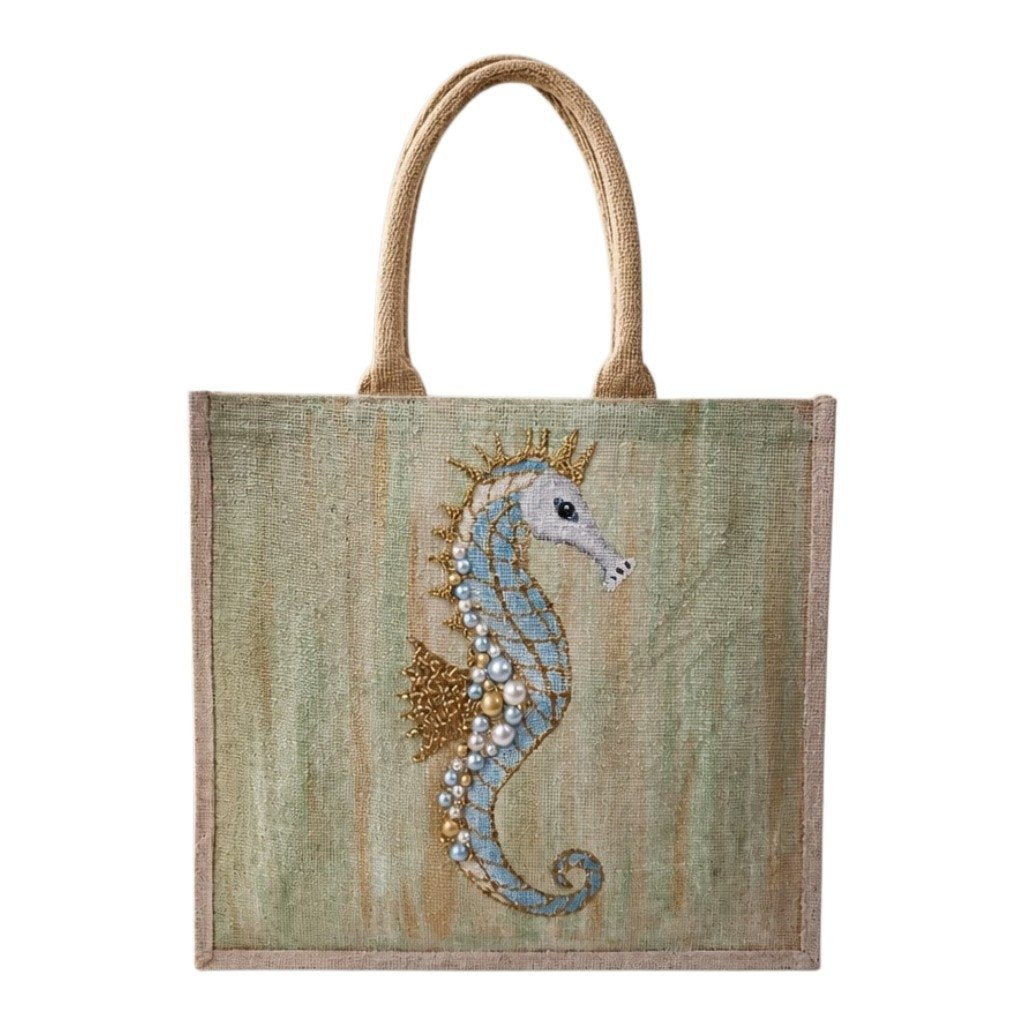 Hand-painted jute tote bag featuring a soft blue seahorse embellished with pearls and gold accents on a textured seafoam green background, finished with natural burlap handles and trim.
