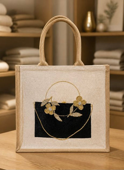 Elegant hand-painted jute tote bag featuring a black rectangular purse design accented with delicate gold floral embellishments, leaves, and a draped gold chain detail. The structured tote has woven natural handles and a sophisticated neutral color palette with artisan-inspired styling.