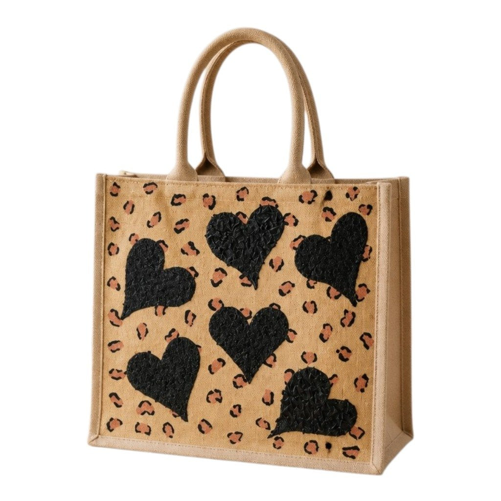 Hand-painted jute shopper bag featuring textured black hearts over a tan background with scattered leopard print accents and natural tan handles.