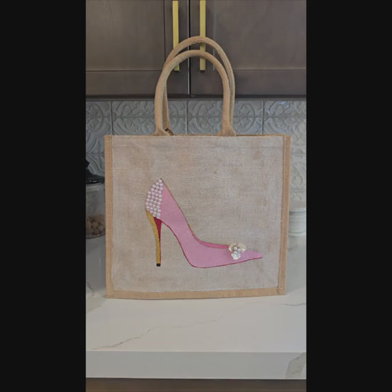 Pink Stiletto hand painted on jute tote bag embellished with jewels and pearls on an off white metallic background.
