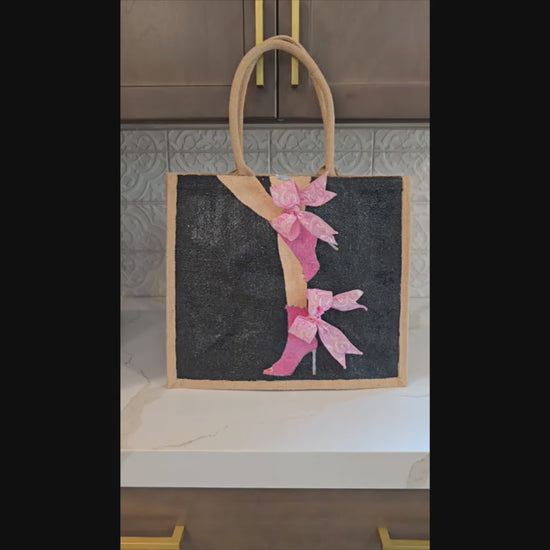 video of Hand-painted tote bag featuring a pink high heel with bows on a black background with dimensional ribbon accents