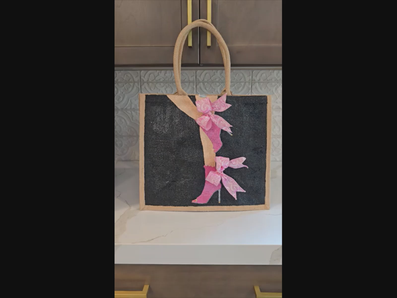 video of Hand-painted tote bag featuring a pink high heel with bows on a black background with dimensional ribbon accents