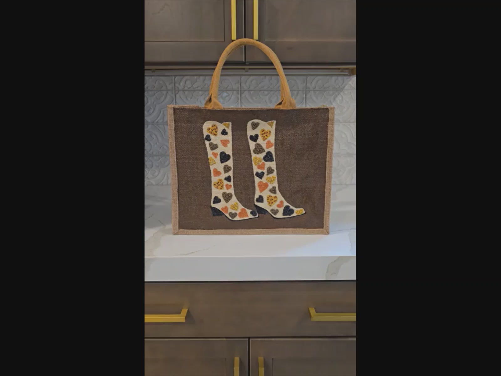 video of Brown jute tote bag with hand-painted cowboy boots decorated in metallic-colored hearts, accented with beads.