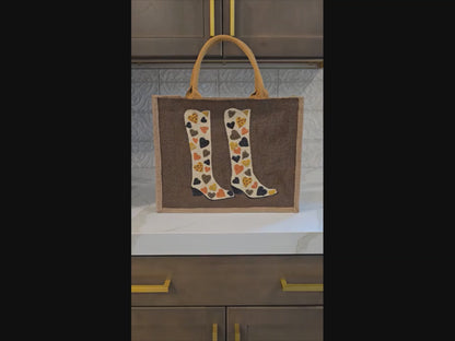 Brown jute tote bag with hand-painted cowboy boots decorated in metallic-colored hearts, accented with beads.