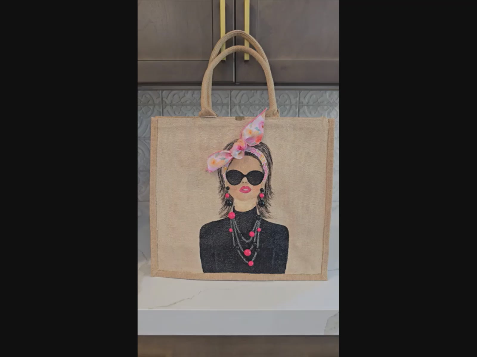 Video of Hand painted jute tote bag featuring a fashion portrait with sunglasses, pink bandana bow, and embellished statement jewelry