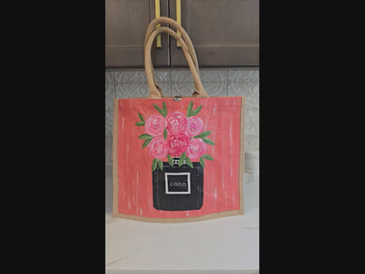 video of Hand painted floral jute tote bag with pink roses and black perfume bottle design