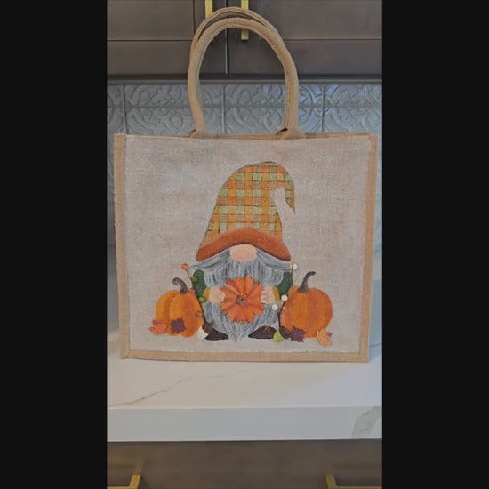 Hand-painted Fall Gnome tote bag with sunflowers, acorns, and berries on metallic jute background