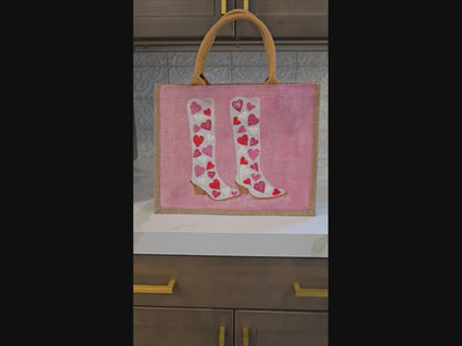 Pink jute tote bag with hand-painted cowboy boots decorated in pink and white hearts, detailed with bead accents.