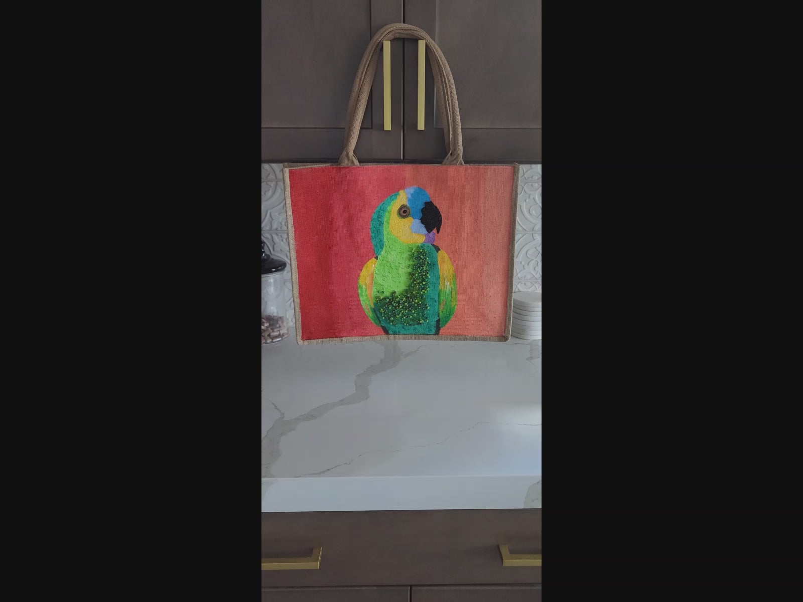 video of parrot on orange tote bag, tropical parrot tote, hand painted parrot jute bag, eco-friendly bird tote
