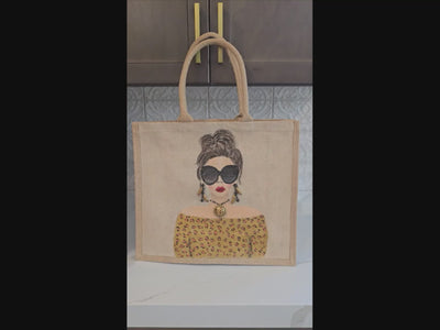 video of Hand-painted jute tote bag featuring a stylish woman with oversized black sunglasses, a leopard print off-the-shoulder top, statement earrings, and layered jewelry on a natural canvas background.