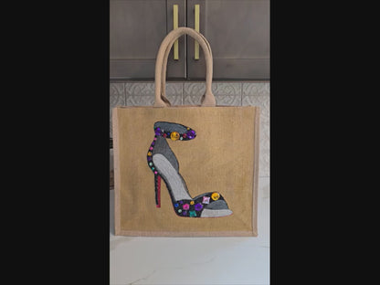 Video with close ups of Hand-painted black stiletto tote bag with gold jeweled accents on natural jute background