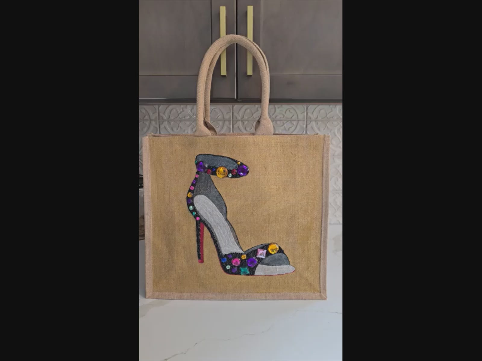 Video with close ups of Hand-painted black stiletto tote bag with gold jeweled accents on natural jute background