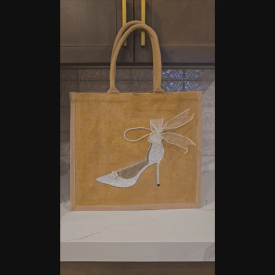 video of Hand-painted jute tote bag featuring an elegant white bridal stiletto with pearl and ribbon details on a natural canvas background