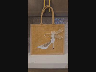 video of Hand-painted jute tote bag featuring an elegant white bridal stiletto with pearl and ribbon details on a natural canvas background