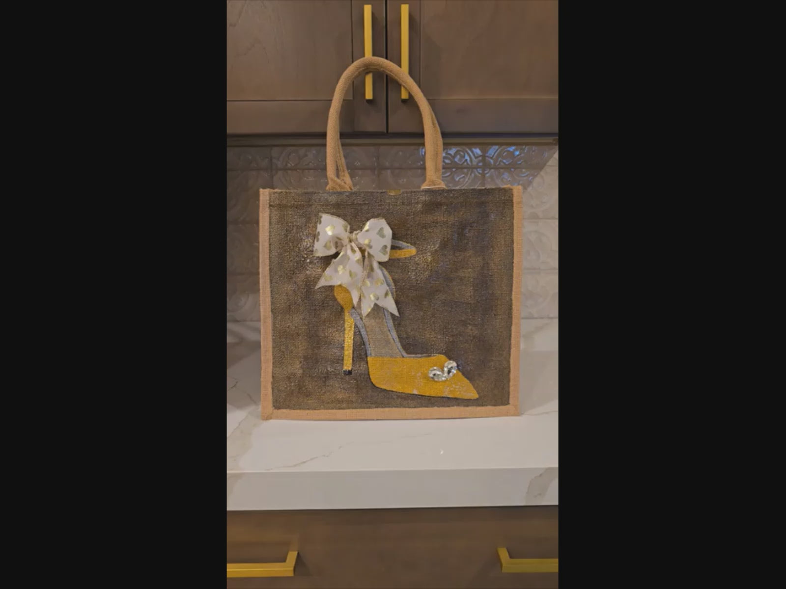 Video of Hand painted and embellished gold stiletto with jeweled heart and cream ribbon with gold heart on bronze background by Dana's Uncommon Glass.