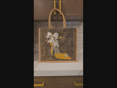 Video of Hand painted and embellished gold stiletto with jeweled heart and cream ribbon with gold heart on bronze background by Dana's Uncommon Glass.