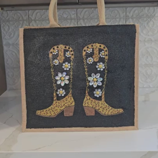 close up video of  Hand-painted black and gold cowboy boot tote bag with jeweled flowers on a black background