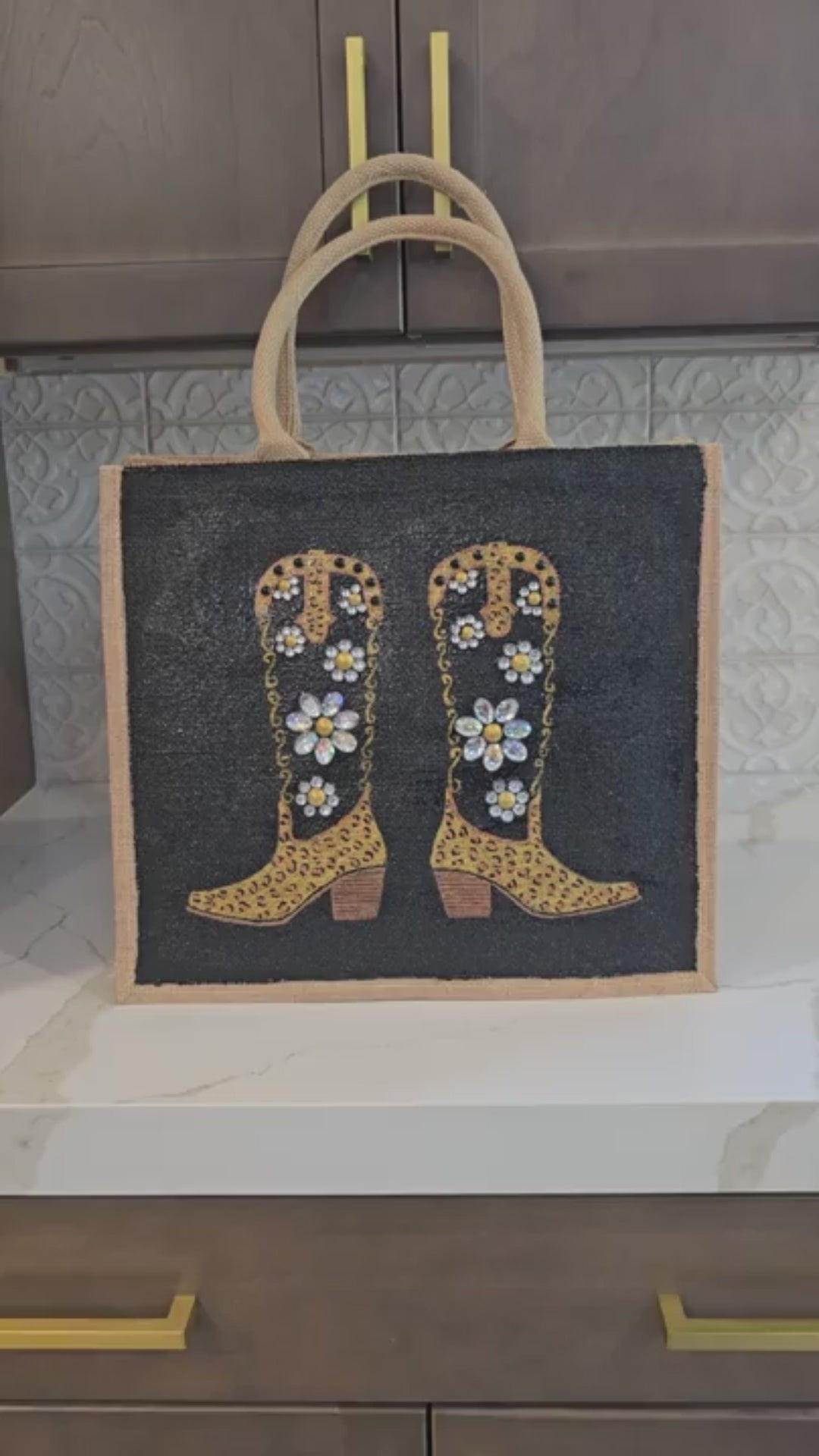 close up video of  Hand-painted black and gold cowboy boot tote bag with jeweled flowers on a black background