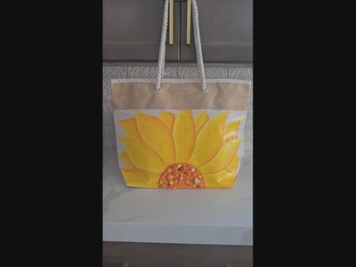 Video of Hand-painted rope handle beach tote featuring a large dimensional yellow sunflower design with textured petals and embellished center details on a natural jute and canvas bag with cream rope handles.