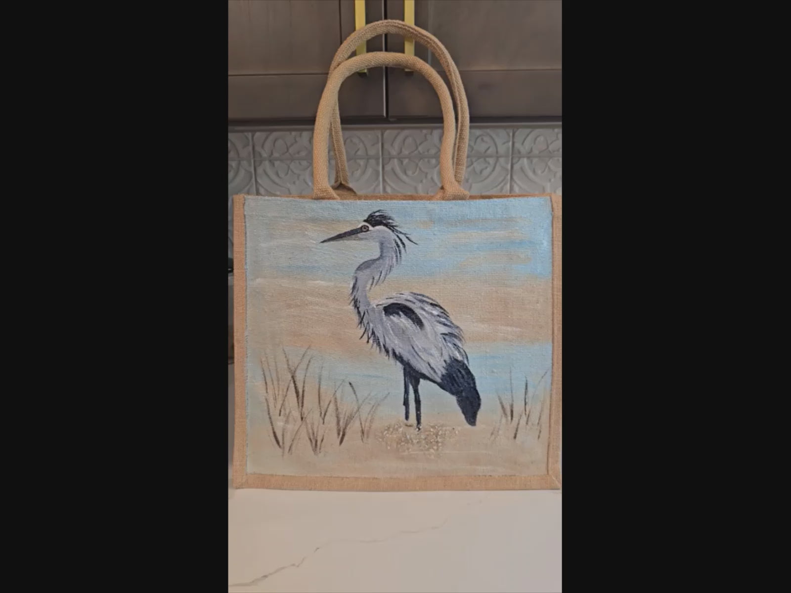 hand painted blue heron with a beachy background embellished with glitter glass on jute tote