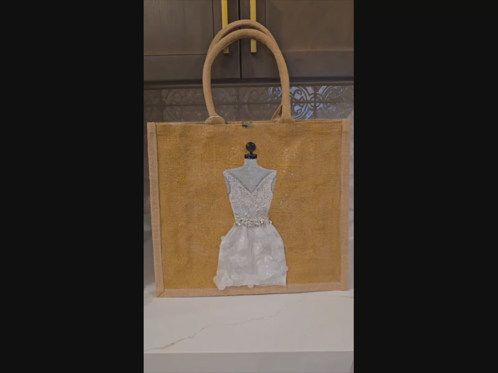 video of Hand-painted jute tote bag featuring an elegant white bridal dress with shimmering details on a natural canvas background