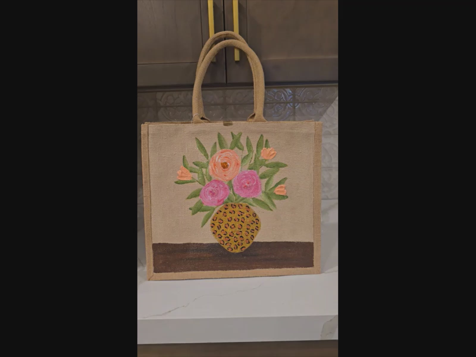 Video of Hand-painted jute tote bag featuring pink and peach flowers arranged in a leopard print vase on a natural canvas background