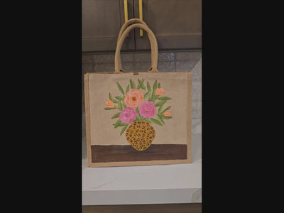 Video of Hand-painted jute tote bag featuring pink and peach flowers arranged in a leopard print vase on a natural canvas background