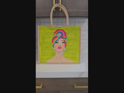 Video of Hand-painted Vivid Muse tote bag featuring a stylish woman with a colorful beaded headwrap, bold makeup, and sparkling jewelry on a vibrant green background, a unique artistic fashion statement bag.