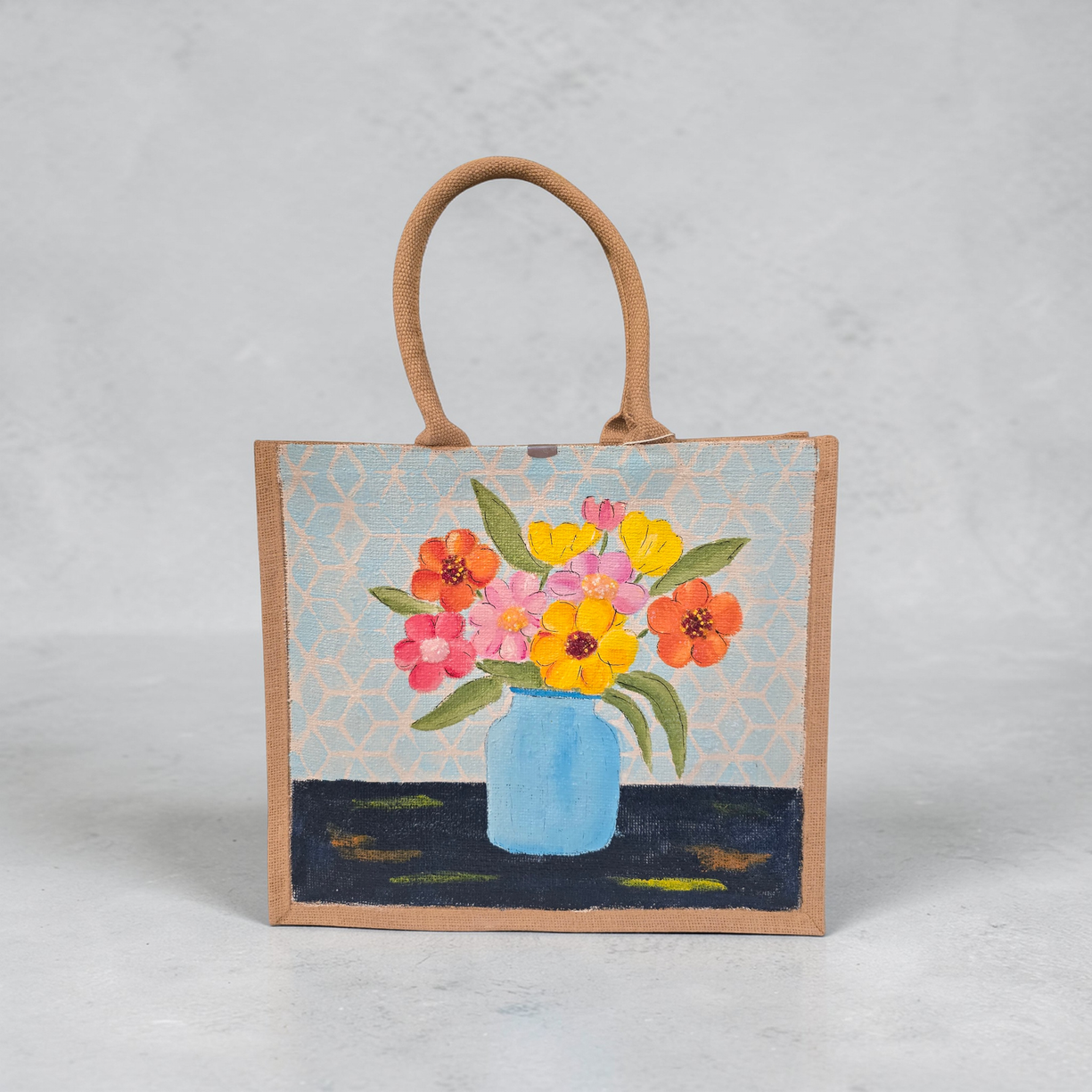 Hand-painted jute tote bag featuring colorful flowers in a blue vase against a light patterned background
