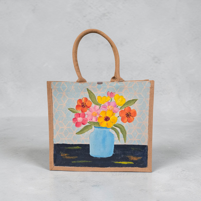 Hand-painted jute tote bag featuring colorful flowers in a blue vase against a light patterned background